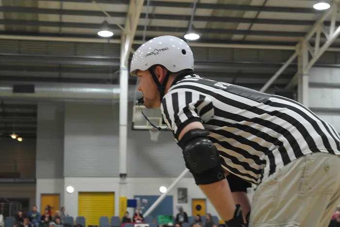 A skating official watching a roller derby bout.